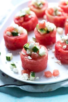 watermelon and feta canapes on a white plate with a blue cloth