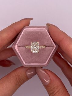 a woman's hands holding an engagement ring in a velvet box with a diamond center