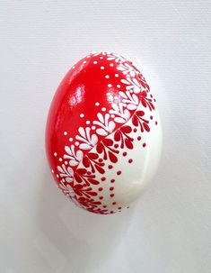 a red and white painted egg on a white surface with floral designs in the center