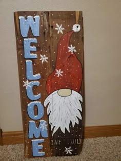 a wooden sign with a gnome's hat and snowflakes on it that says welcome