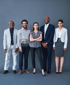 a group of people standing next to each other in front of a gray wall with their arms crossed