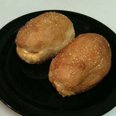 two doughnuts sitting on top of a black plate next to a white counter