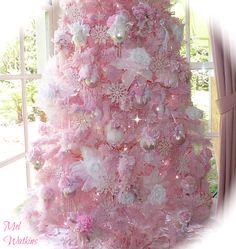 a pink christmas tree is decorated with white and pink flowers, ornaments, and pearls