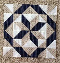 a close up of a patchwork quilt on the floor with white and blue squares