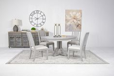 a white table with four chairs and a large clock on the wall in the background