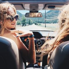 two women sitting in the driver's seat of a car