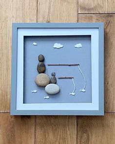 a shadow frame with rocks and fishing rods in it on a wooden floor next to a wall