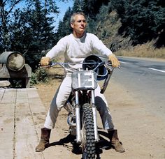 a man riding on the back of a motorcycle down a road