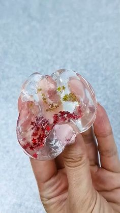 a hand holding a small glass object in it's left hand, with red and white flowers on the inside