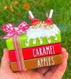 a hand holding a small wooden box with apples on it and the words caramel apples