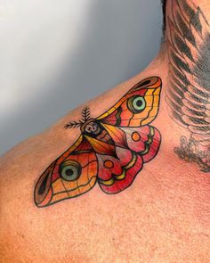 a man's chest with a colorful butterfly tattoo on the side of his neck