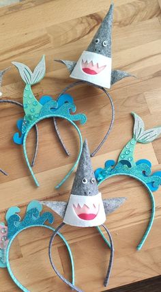 three paper hats made to look like mermaids with mouths and teeth on the heads