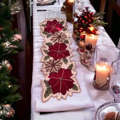 the table is set with candles, plates and napkins for christmas dinner guests to enjoy