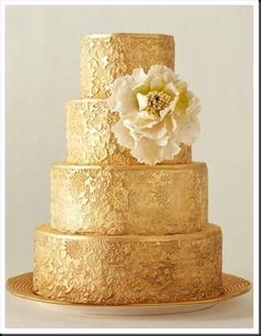 a gold wedding cake with white flowers on top