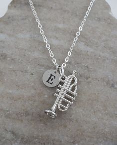 Silver plated trumpet necklace with a personalized monogram antique silver initial charm. It makes a great gift for musicians. This necklace includes: - trumpet charm (size 25 x 10 mm | 3/8 x 1 inch) - stainless steel initial charm (size 9 mm | 3/8 inch) - silver anchor chain (14 to 36 inches) To Add Initial or Number Charms: https://etsy.me/3RnJ5qD  To Add Birthstone Charms: https://etsy.me/3Zif2Uw Looking for more jewelry? Visit our shop: https://cppewter.etsy.com ♥ SHIPPING INFO ♥ We ship twi Silver Initial Charms, Antique Silver Jewelry, Anchor Chain, Musician Gifts, Necklace Antique, Birthstone Charms, Personalized Monogram, Necklace Personalized, Initial Charm