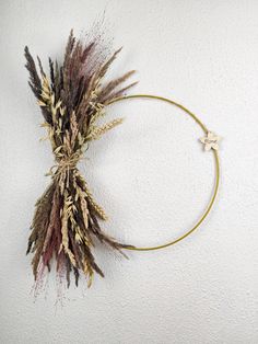 dried flowers are arranged in a circle on a white wall with a gold star hanging from the middle