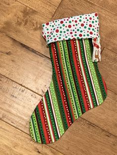 a christmas stocking on the floor with red, green and white stripes