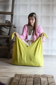 a woman sitting on the floor with a large yellow bag in front of her face