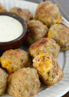 a white plate topped with meatballs next to a bowl of ranch dressing