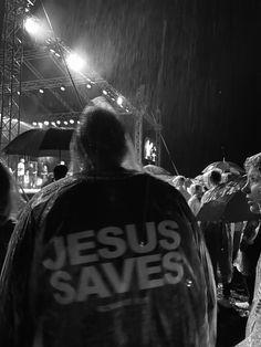 a group of people standing around each other under an umbrella in the rain at night