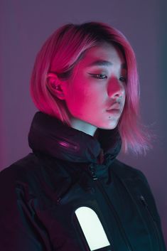 a woman with pink hair wearing a black jacket and looking off to the side in neon light