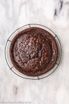 a chocolate cake sitting on top of a white marble counter next to a wire rack