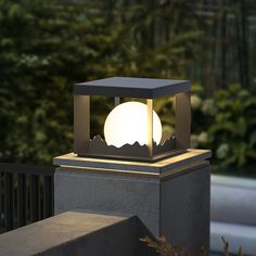 a light that is sitting on top of a cement block in front of some trees