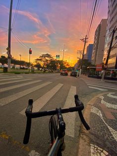 a bike is parked on the side of the road at an intersection as the sun sets