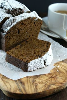 a loaf of bread sitting on top of a wooden cutting board next to a cup of coffee