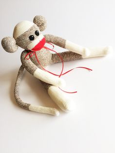 a sock monkey with a red string tied to it's back on a white surface