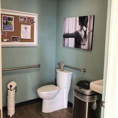 a bathroom with a toilet, trash can and pictures on the wall