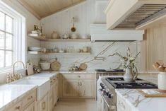 a kitchen with marble counter tops and white cabinets, along with open shelving above the stove