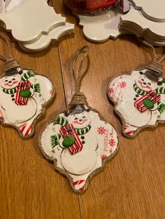 three snowman ornaments are hanging from twine on the floor next to a mirror