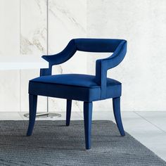 a blue chair sitting on top of a rug next to a white table and wall