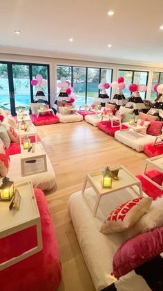 a room filled with lots of white and red couches covered in pillows next to large windows