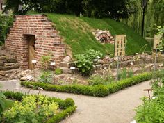 an outdoor garden with a brick structure and green grass on the hill side, surrounded by trees