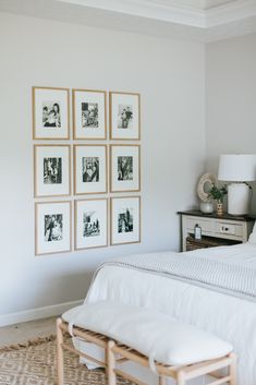 a white bed sitting in a bedroom next to pictures on the wall