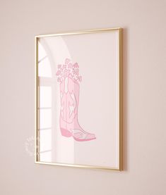 a pink cowboy boot with flowers on it is framed in a gold frame against a white wall