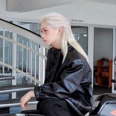 a woman sitting on top of a motorcycle next to a stair case in front of a building