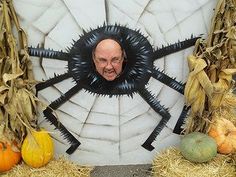 a man is smiling in front of a fake spider