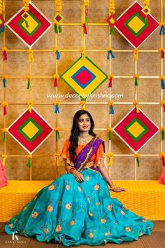 a woman sitting on top of a yellow bench in front of a wall with colorful decorations