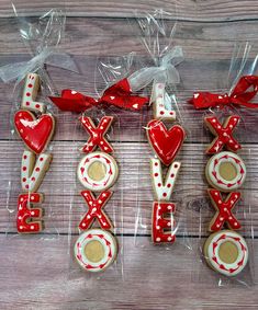 decorated cookies in the shape of xoxo and two hearts on a wooden table