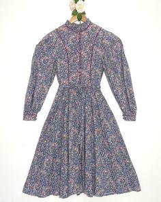 Vintage 1970's Origin dress made with Liberty of London fabric.  A gorgeous floral dress, with the classic Origin button up front. Very regencycore with its large beautiful bishop sleeves.  Measurements:  Pit to pit: 17ins Waist, laid flat: 14ins Full length: 45.5ins Condition: Some signs of wear but in good vintage condition. #VintageDress #FloralDress #OriginDress #OriginLiberty #BishopSleeves Victorian Prairie Dress With Long Sleeves For Daywear, Victorian Style Long Sleeve Prairie Dress For Daywear, Spring Victorian Long Sleeve Vintage Dress, Regency Style Long Sleeve Prairie Dress For Fall, Victorian Long Sleeve Prairie Dress For Fall, Pastoral Prairie Dress With Floral Print, Cottagecore Prairie Dress With Floral Print For Daywear, Vintage Blue Victorian Daywear Dress, Vintage Floral Print Prairie Dress For Garden Party