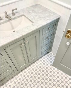 a bathroom with grey cabinets and a white sink