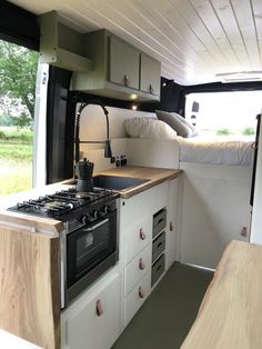 a kitchen area with an oven, sink and bed in a campervane