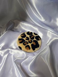 an animal print brooch sitting on top of a white satin material covered in black and brown fur