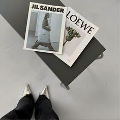 a person standing on the ground with their feet propped up next to an open magazine