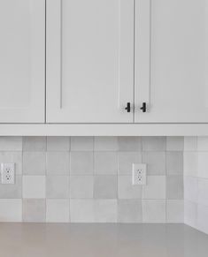 a kitchen with white cabinets and tile backsplashes on the counter top,