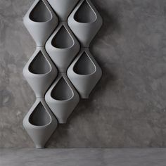 a wall mounted vase sitting on top of a cement floor next to a gray wall