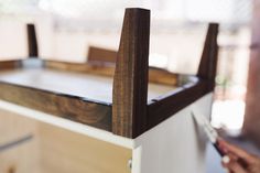 a close up of a person holding a knife and cutting something on a wooden table